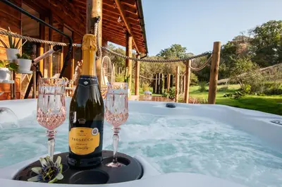 a bottle of champagne and two glasses on a table at The Chard, Netherby, a micro cabin in a rural setting with a hot tub in Longtown