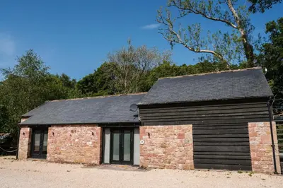 a stone and brick building with a black roof at The Heronry, Netherby, a luxurious cottage ideal for a romantic break with hot tub in a rural setting in Longtown