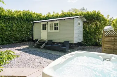 a bath tub in a yard with a shed at The Snug, Netherby, cute shepherds hut with hot tub in a rural location in Longtown