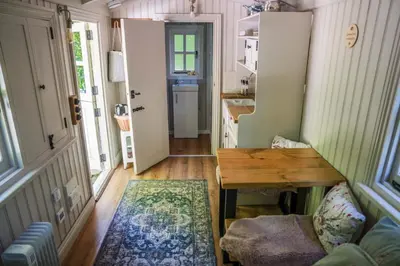 a tiny house with a kitchen and a table at The Snug, Netherby, cute shepherds hut with hot tub in a rural location in Longtown