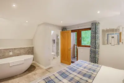 a bathroom with a bed and a bath tub and a sink at Lord Galloway 36 with Hot Tub in Newton Stewart