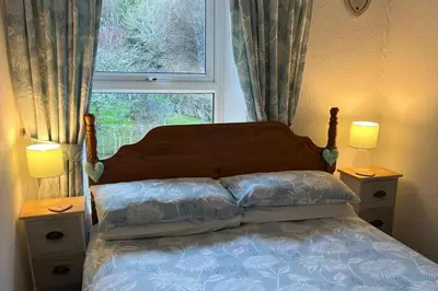 a bedroom with a bed with a window and two night stands at Cottage - Sleeps 4 - Pets Ok - Garden - Parking in Keswick
