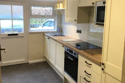 a kitchen with white cabinets and a black stove top oven at Cottage - Sleeps 4 - Pets Ok - Garden - Parking in Keswick