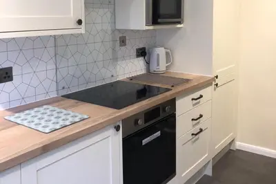 a kitchen with white cabinets and a black appliance at Cottage - Sleeps 4 - Pets Ok - Garden - Parking in Keswick