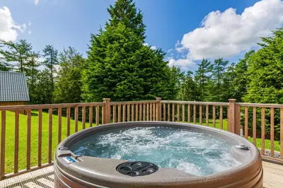 a hot tub on a deck with a wooden fence at Lord Galloway 37 with Hot Tub in Newton Stewart