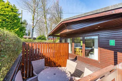 a deck with a table and chairs on a house at Birch Lodge 12 with Hot Tub in Newton Stewart