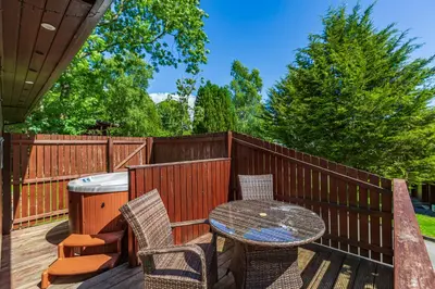 a patio with a table and chairs on a deck at Bluebell Lodge 3 with Hot Tub in Newton Stewart