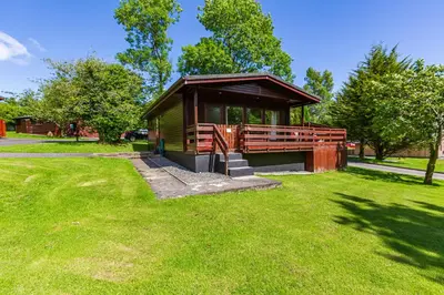a small building in a park with green grass at Bluebell Lodge 3 with Hot Tub in Newton Stewart