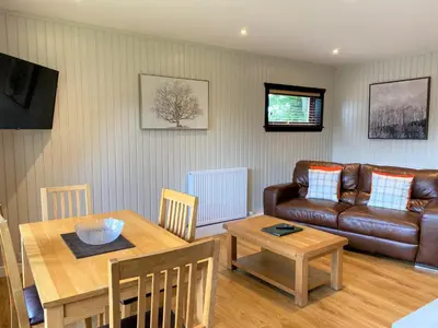 a living room with a table and a couch at Birch Lodge 17 with Hot Tub in Newton Stewart