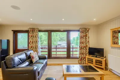 a living room with a leather couch and a television at Bluebell Lodge 4 with Hot Tub in Newton Stewart