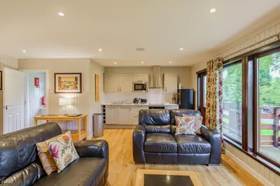 a living room with two leather couches and a kitchen at Bluebell Lodge 4 with Hot Tub in Newton Stewart