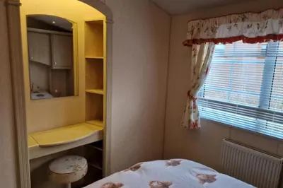 a bedroom with a bed and a mirror and a window at Caravan - Sleeps 4 - Pet friendly - Parking in Newton Stewart