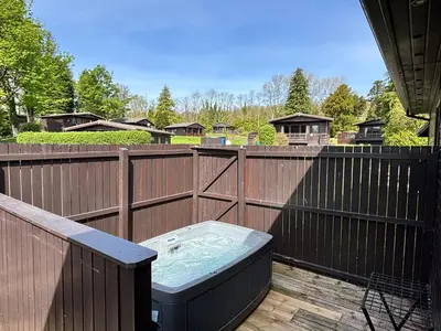 a hot tub on a deck with a fence at Bluebell Lodge 5 with Hot Tub in Newton Stewart