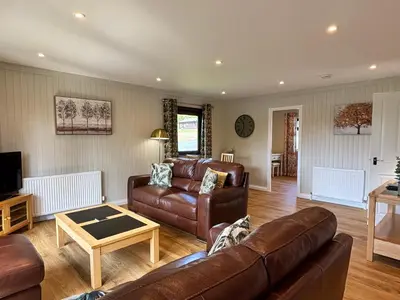 a living room with a couch and a table at Bluebell Lodge 5 with Hot Tub in Newton Stewart