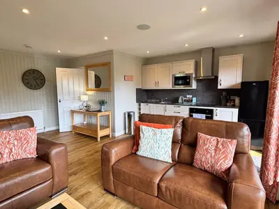 a living room with a couch and a kitchen at Bluebell Lodge 9 with Hot Tub in Newton Stewart