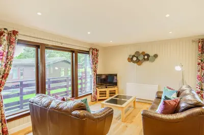 a living room with two leather couches and a television at Bluebell Lodge 10 with Hot Tub in Newton Stewart