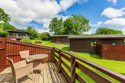 a patio with a table and chairs on a deck at Bluebell Lodge 11 with Hot Tub in Newton Stewart