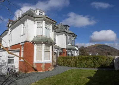 an old house with a mountain in the background at Loft Apartment, Keswick in Keswick
