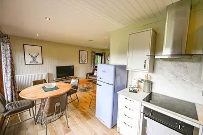 a kitchen with a table and a refrigerator and a dining room at Birch Lodge 14 with Hot Tub in Newton Stewart