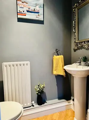 a bathroom with a sink and a toilet and a mirror at Sunset House On The Beach in Maryport
