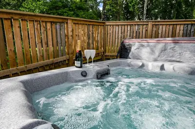 a hot tub with a bottle of wine in it at Birch Lodge 18 with Hot Tub in Newton Stewart