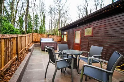 a patio with chairs and a table and a fence at Birch Lodge 18 with Hot Tub in Newton Stewart