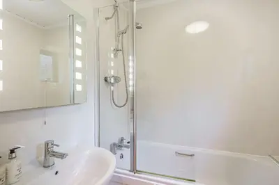 a white bathroom with a shower and a sink at Birch Lodge 19 with Hot Tub in Newton Stewart