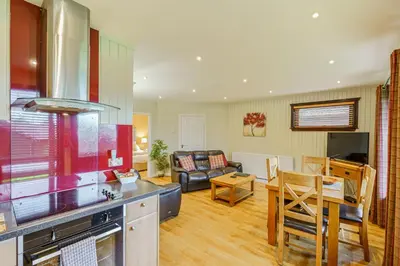 a kitchen and living room with a couch and a table at Birch Lodge 19 with Hot Tub in Newton Stewart