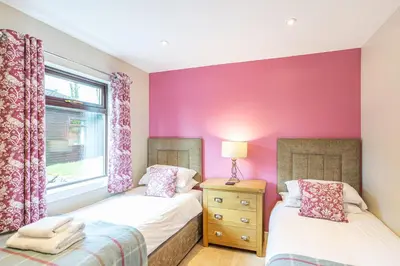 two beds in a room with pink walls at Birch Lodge 20 with Hot Tub in Newton Stewart