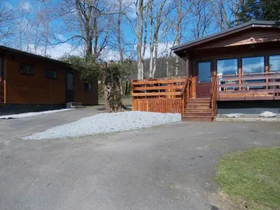 a house with a wooden fence and a porch at Birch Lodge 22 with Hot Tub in Newton Stewart