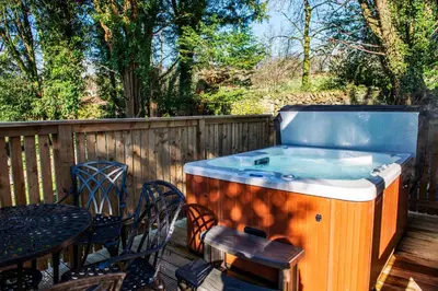 a hot tub on a deck with a table and chairs at Birch Lodge 23 with Hot Tub in Newton Stewart