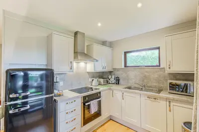 a kitchen with white cabinets and a black refrigerator at Birch Lodge 23 with Hot Tub in Newton Stewart