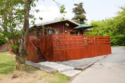 a wooden fence with a house behind it at Laurel Lodge 6 with Hot Tub in Newton Stewart