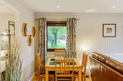 a dining room with a table and a window at Conifer Lodge 8 with Hot Tub in Newton Stewart