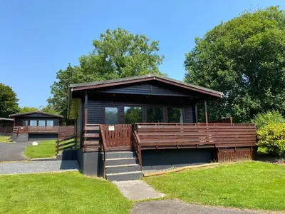 a kiosk in a park with a bench and grass at Conifer Lodge 8 with Hot Tub in Newton Stewart