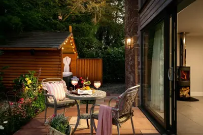 a patio with a table and chairs and a shed at Daisy Cottage, Dalston, peaceful, rural setting with garden & hot tub in Carlisle
