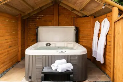 a bathroom with a tub in a wooden house at Daisy Cottage, Dalston, peaceful, rural setting with garden & hot tub in Carlisle