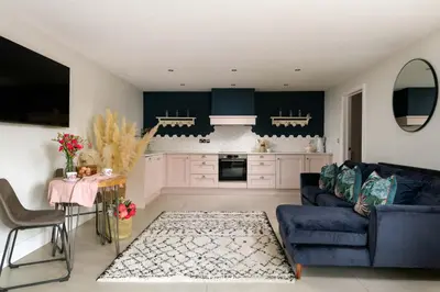 a living room with a blue couch and a kitchen at Daisy Cottage, Dalston, peaceful, rural setting with garden & hot tub in Carlisle