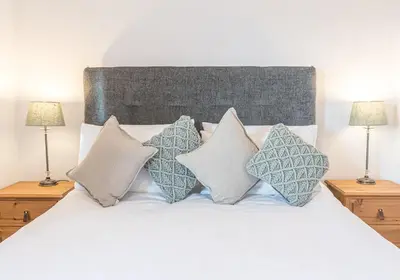 a bedroom with a bed with four pillows at Lilac Cottage in Keswick