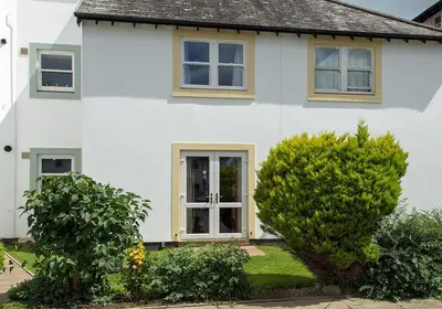 a white house with two bushes in front of it at Lilac Cottage in Keswick