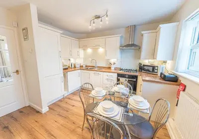 a kitchen with white cabinets and a table and chairs at Lilac Cottage in Keswick