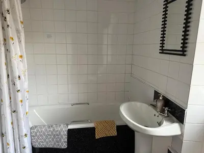 a white bathroom with a sink and a tub and a sink at 16 Main Street in St Bees