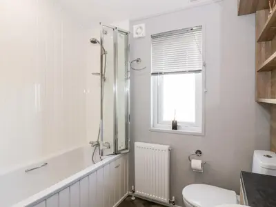 a bathroom with a shower and a toilet and a sink at Dershel Lodge in Dumfries