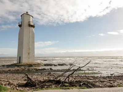 a lighthouse on the shore of a body of water at Dershel Lodge in Dumfries