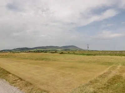a field of grass with mountains in the background at Dershel Lodge in Dumfries