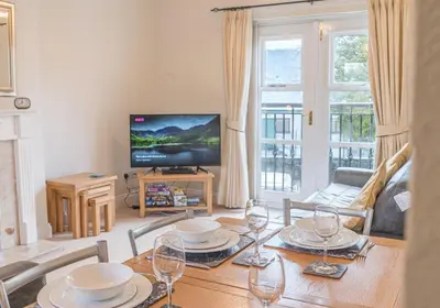 a living room with a table and a television at 16 Greta Grove House in Keswick