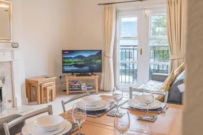 a living room with a table and a television at 16 Greta Grove House in Keswick