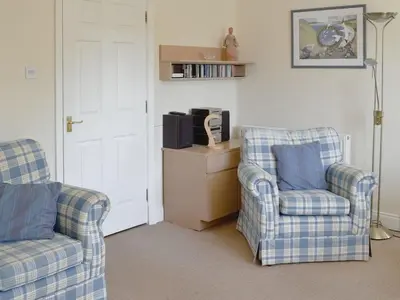 a living room with two chairs and a tv at 9 Greta Grove House in Keswick