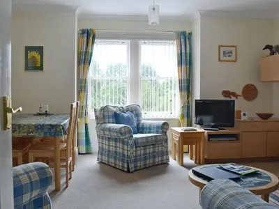 a living room with a chair and a table at 9 Greta Grove House in Keswick
