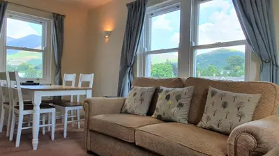 a living room with a couch and a table and windows at Skiddaw. 20 Greta Grove House in Keswick